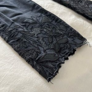 Black denim crop pants with leather and lace detail at cuffs.
